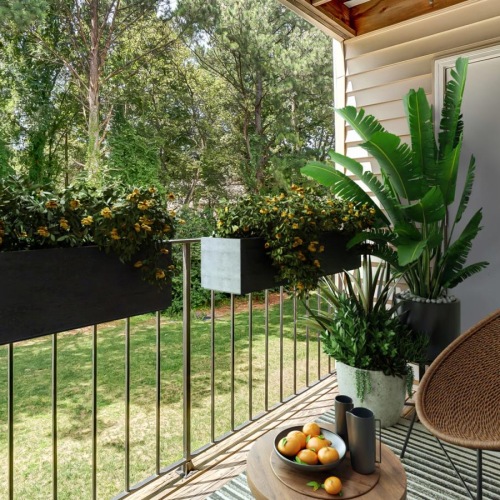a table with a chair and plants on it by a fence and trees